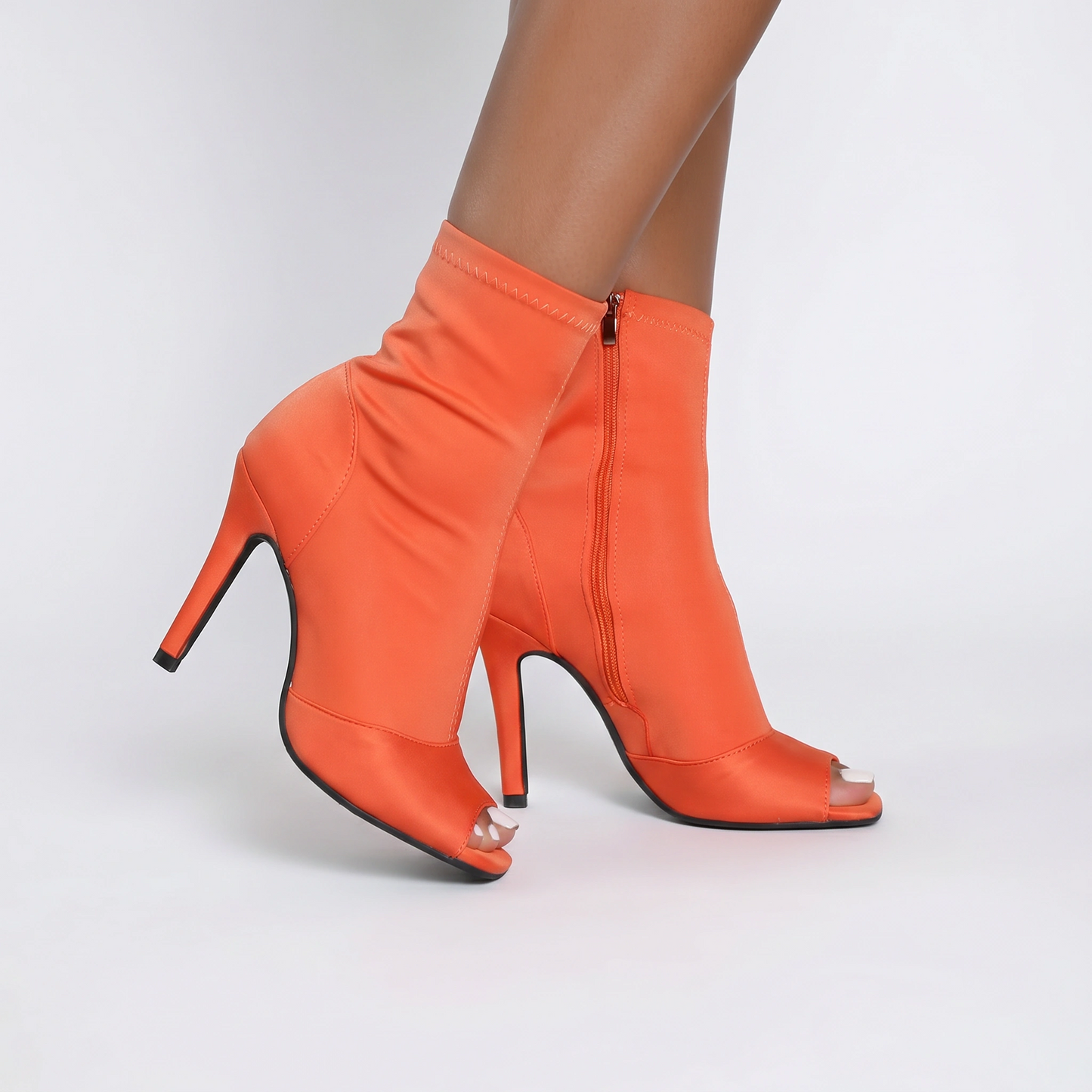 Orange high-heeled ankle boots with open toes on a white background