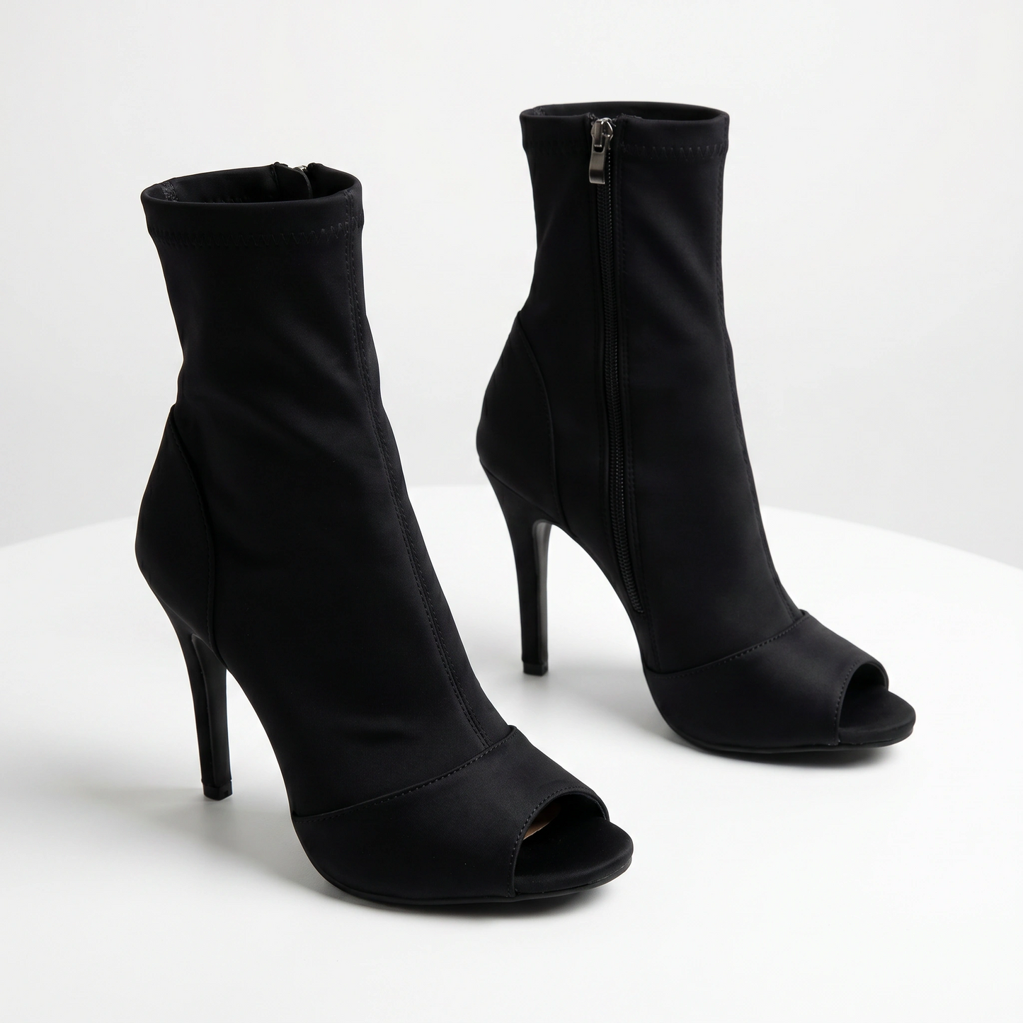 Black high-heeled open-toe ankle boots on a white background