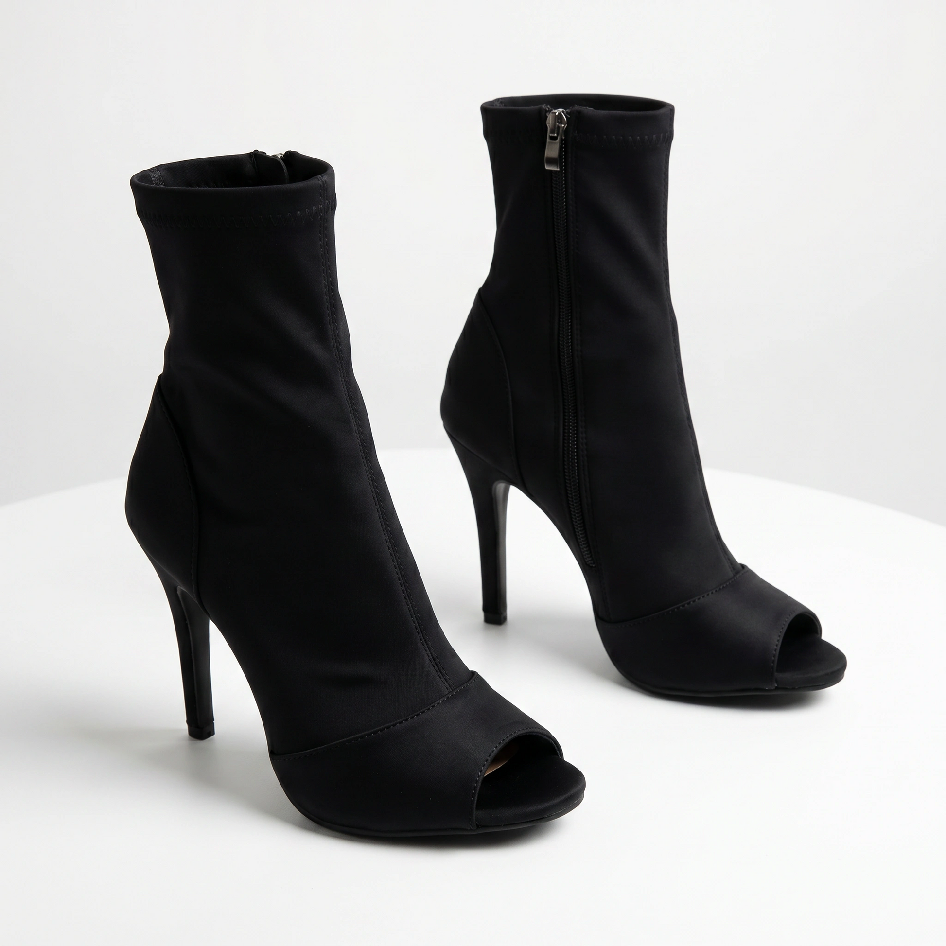 Black high-heeled open-toe ankle boots on a white background