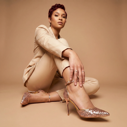 Woman wearing a beige suit and glittery high heels on a beige background