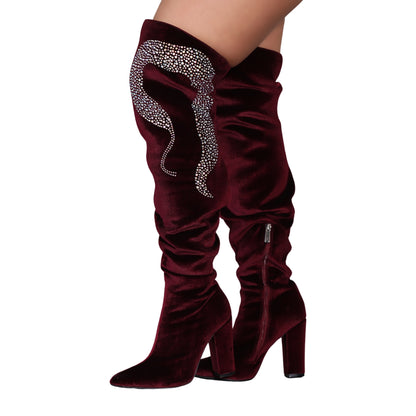Crimson knee-high velvet boots with high block heels and rhinestone snake design on outer side