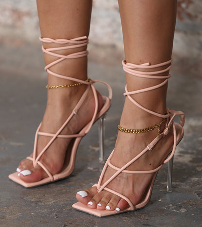 Bonia strappy pale pink stiletto heels with clear high heels and gold ankle chains on feet
