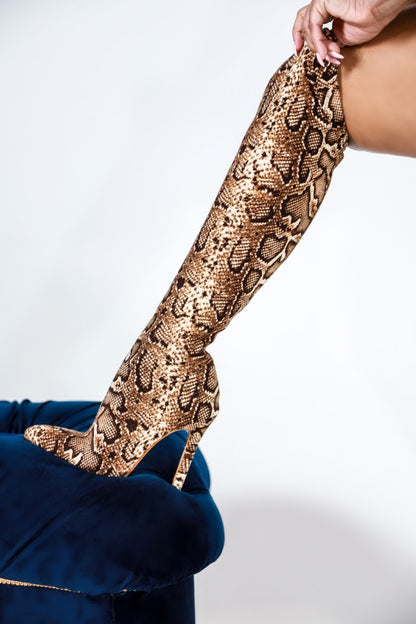 Tiosebon Snake Boots featuring knee-high snake print design with pointed toe and high stiletto heels on a blue velvet surface