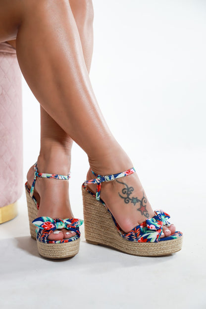 Tory colorful floral wedge sandals with ankle straps and woven platform heels on model’s feet